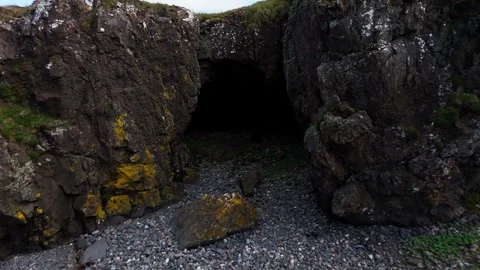 Aerial Dolly Forward Toward Dark Coastal Cave Entrance on Rocky Shore Vídeos de archivo 333767570