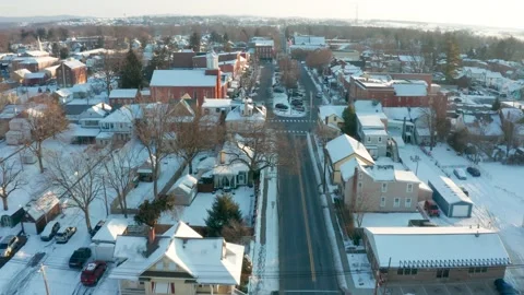 Aerial dolly shot approaching town square in winter snow. American flag Stock Footage