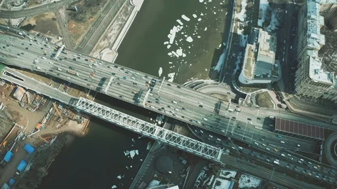 Aerial down view of cars moving along the bridge across icy river Stock Footage 105123711