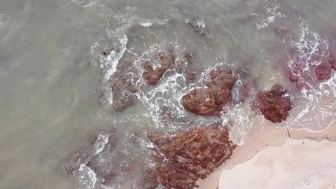 Aerial down view of waves smashing beautiful rocks by the beach Stock Footage 156939398