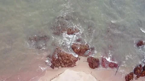 Aerial down view of waves smashing beautiful rocks by the beach Stock Footage 156939425