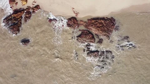 Aerial down view of waves smashing beautiful rocks by the beach Stock Footage 156939460