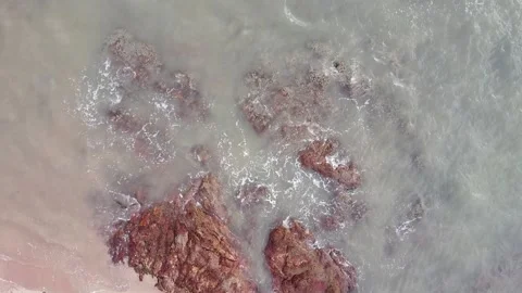 Aerial down view of waves smashing beautiful rocks by the beach Stock Footage 156939482