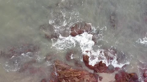 Aerial down view of waves smashing beautiful rocks by the beach Stock Footage 156939493