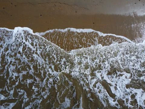 Aerial down view of whit waves washing on the beach Stock Photos