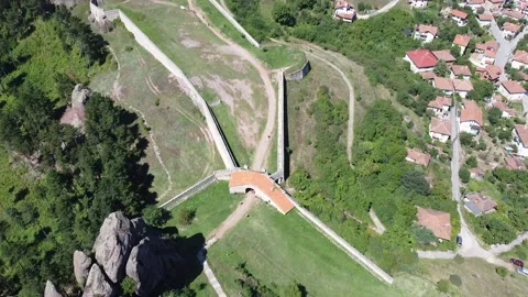 Aerial downwards tilt up shot above rocky mountains showing village in Bulgaria Stock Footage