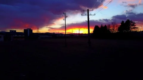 AERIAL: Dramatic colorful sunset behind mountains in small industrial town Stock Footage 80846919