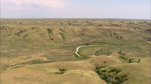 Aerial of dried river bed through rolling hills covered with grass, Flight Over Stock Footage 109459076