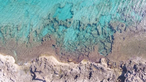 AERIAL DRON TOP DOWN ROCKY COST AND SAND WITH TURQUOISE WATER Stock Footage 130134485