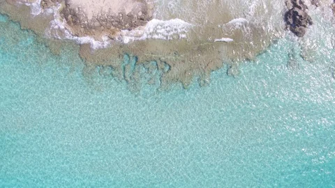 AERIAL DRON TOP DOWN TURQUOISE WATER WITH COAST ROCKS AND SAND Stock Footage 130134612