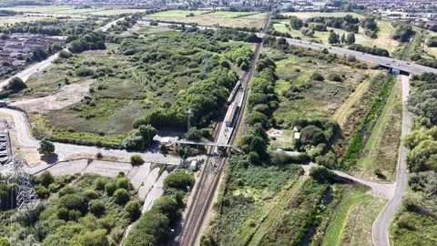 Aerial drone 4K view of Merseyside rail line beside warm sunlit greenery Video stock 343159641