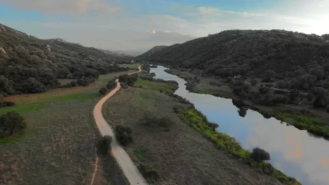 Aerial drone 4k view of river valley and dirt country road at sunset Stock Footage 115996477