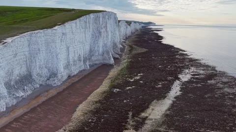 Aerial drone approach to white cliff and textured coastline with calm sea Stock Footage 309765254