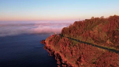 Aerial Drone Approaching Lighthouse Through Mist at Red Sunset Stock Footage 339368441