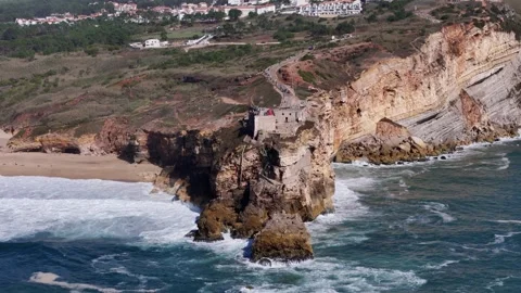 Aerial drone approaching the stunning cliffs and famous lighthouse at Nazare Stock Footage 287730657