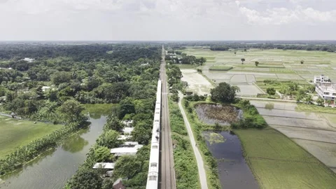 Aerial drone ascending as passenger train moves forward through rural landscape Stock Footage 344544287