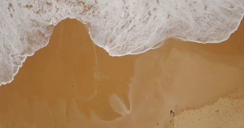 Aerial Drone camera birdseye view sandy beach waves washing shoreline daylight Stock Footage 73504191