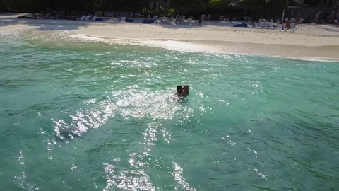 The aerial drone camera flies around couple swimming in Indian ocean on an empty Stock Footage