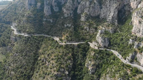 Aerial drone camera flying toward mountainous road cars driving near rock cliffs Stock Footage 113702893