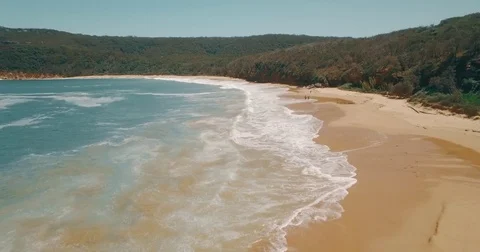 Aerial Drone camera view flying along secluded beach shoreline waves daylight Stock Footage 73569840