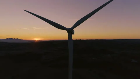AERIAL DRONE CLOSE UP ORBIT OF WIND TURBINE BLADES SPINNING WITH SUNSET Stock Footage 130339662