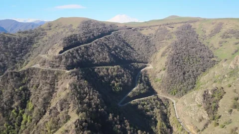 Aerial drone descent over winding serpentine road to Jily-Su with Mount Elbrus Stock Footage 337023760