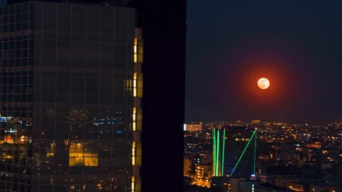 Aerial drone distant view super full moon rising over European skyline at night Stock Footage 128226135
