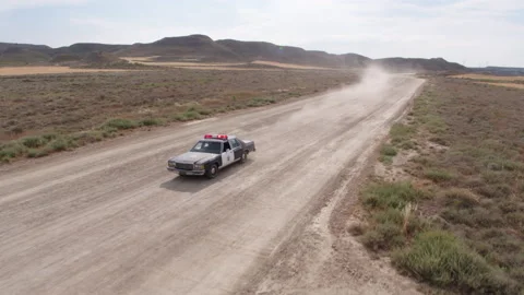 AERIAL DRONE FAST PERSECUTION SHERIFF POLICE CAR IN A DUSTY DESERT ROAD Stock Footage