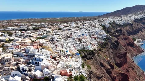 Aerial drone flies above dense whitewashed Oia town Vidéo 344995984