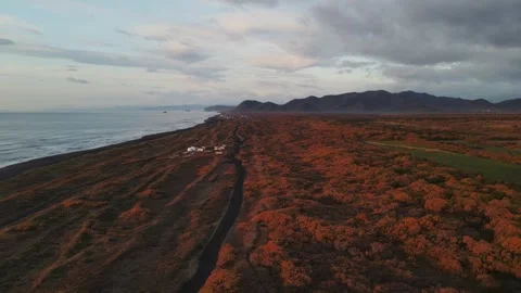 An aerial drone flies over an evening beach with black volcanic sand Stock Footage 280379166