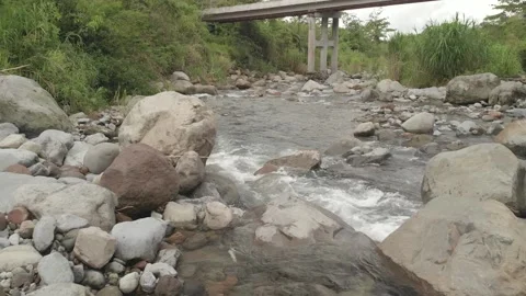 Aerial. Drone flies over shallow river passing under a bridge. HD. Video stock 139065553