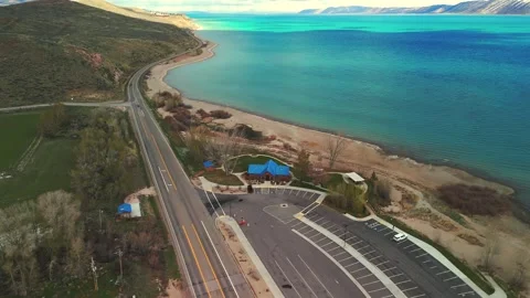 Aerial drone flight along Bear Lake Utah shoreline with road and turquoise water Stock Footage 335080644