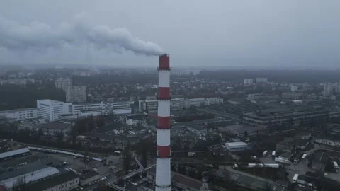 Aerial drone flight approaching industrial smokestack over city in winter Stock Footage 341767133