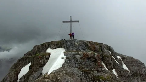 Aerial drone flight from mountain top summit with cross and hikers in foggy Video stock 80647616