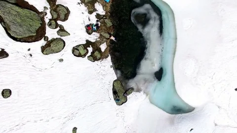 Aerial drone flight over blue small lake in the snow with hikers in alpine Video stock 80541213