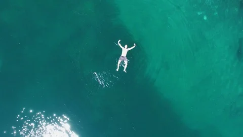 Aerial drone flight over calm, blue, turquoise mountain lake with swimmer and Video stock 91014053