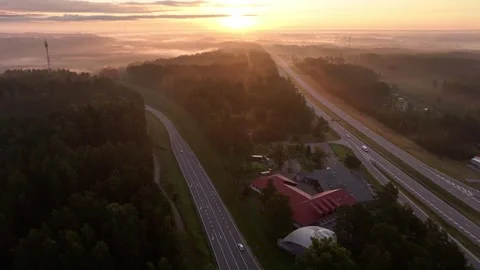 Aerial Drone Flight Over Modern Highway at Sunrise Through Misty Forest Stock Footage 345323993