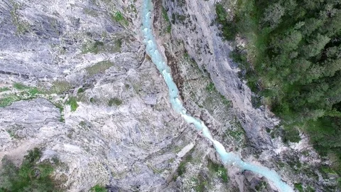 Aerial drone flight over river in a valley with rocks between green fir tree Video stock 80591814