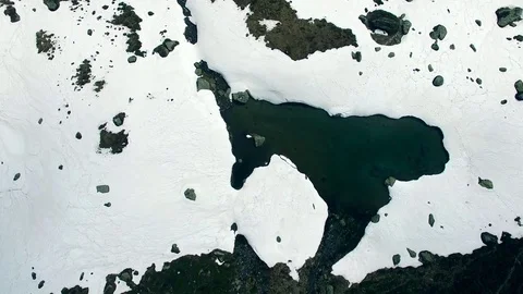 Aerial drone flight over small lake water in the snow with hikers in alpine Stock Footage 80541802