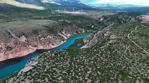 Aerial drone flight over turquoise river canyon in Croatia with wind turbines Stock Footage 337614855