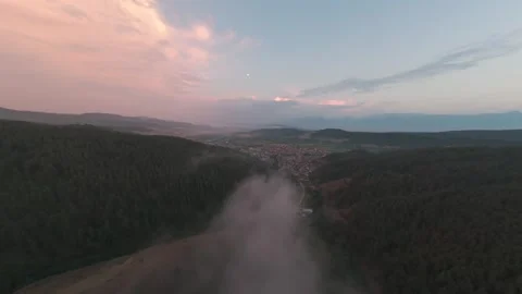 Aerial drone flight toward Belitsa over forest and low fog at sunset in Bulgaria Stock Footage 343686401
