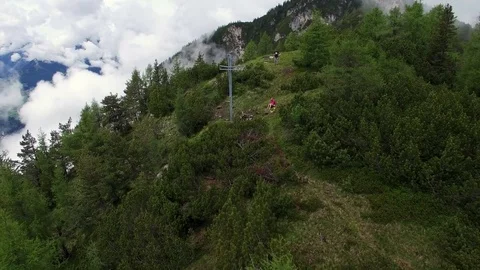 Aerial drone flight toward summit cross with young hikers in fir trees and Video stock 80541091