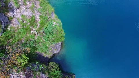Aerial drone flight of young guy jumping backflip into blue mountain lake on Video stock 91014862