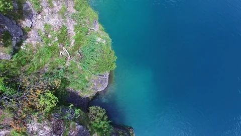 Aerial drone flight of young guy making back flip into blue mountain lake on 스톡 동영상 91014914
