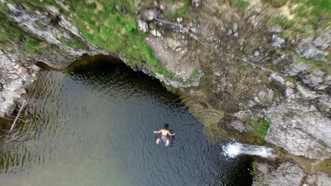 Aerial drone flight of young man jumping with back flip off cliff into mountain 스톡 동영상 80571077