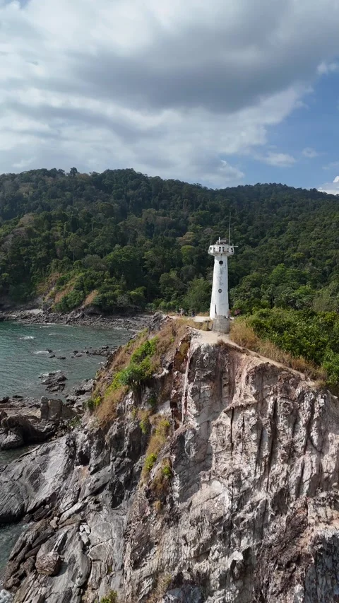 Aerial Drone Flying Away from Lighthouse on Rocky Coastal Cliff in Koh Lanta, Stock Footage 335950899