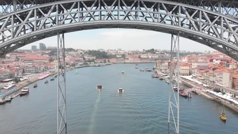 Aerial: Drone flying beneath the main arch of Dom Luis I Bridge with boats on 스톡 동영상 345108422