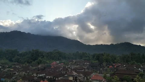Aerial Drone Flying Forward Over Traditional Village in Bali and Sacred Mountain Vídeo Stock 327120624