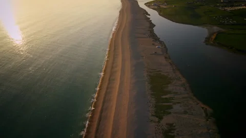 Aerial drone flying over a sandy coastline at sunrise Video stock 336364615