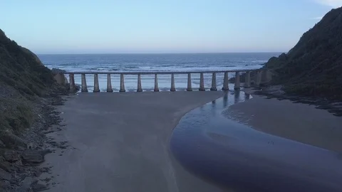 Aerial drone flying under a large bridge highway on the coastline where a Stock Footage 98902906